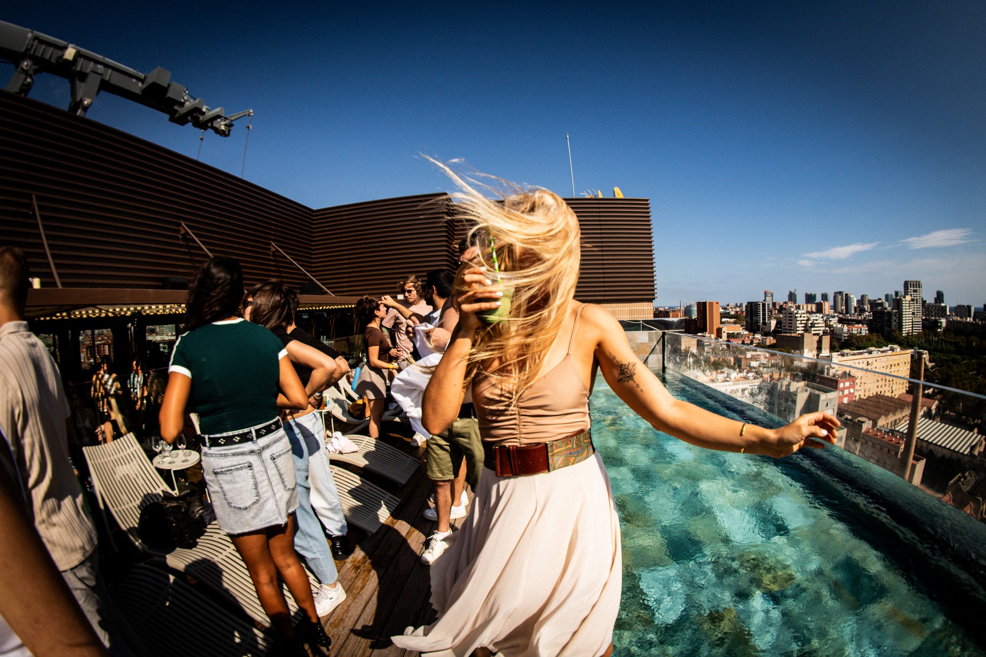 Woman on a rooftop with a cityscape view during a matcha rave, enjoying a iced matcha latte.